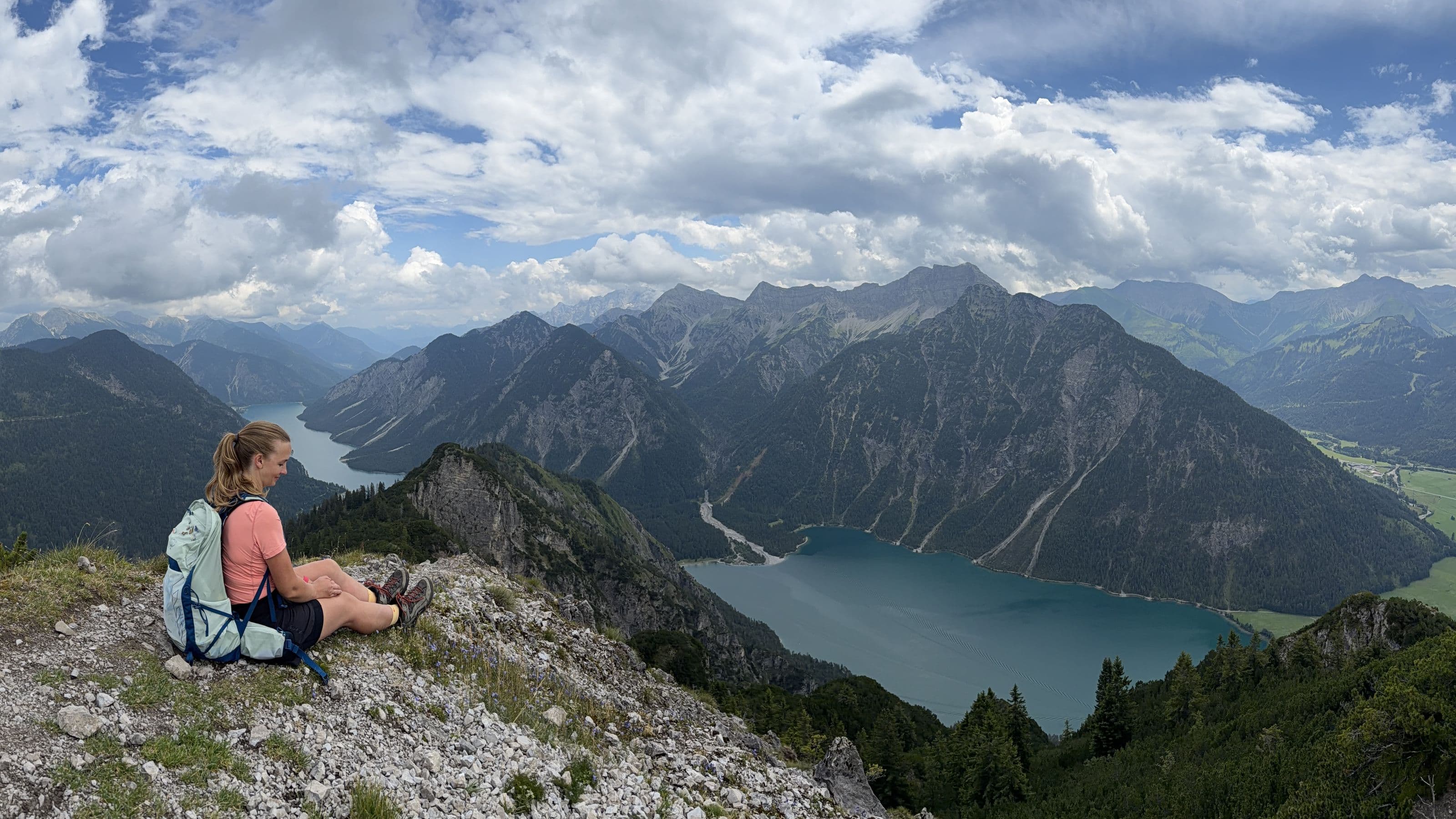 Anja sitzt auf einem Grat über einem Bergsee in den Alpen