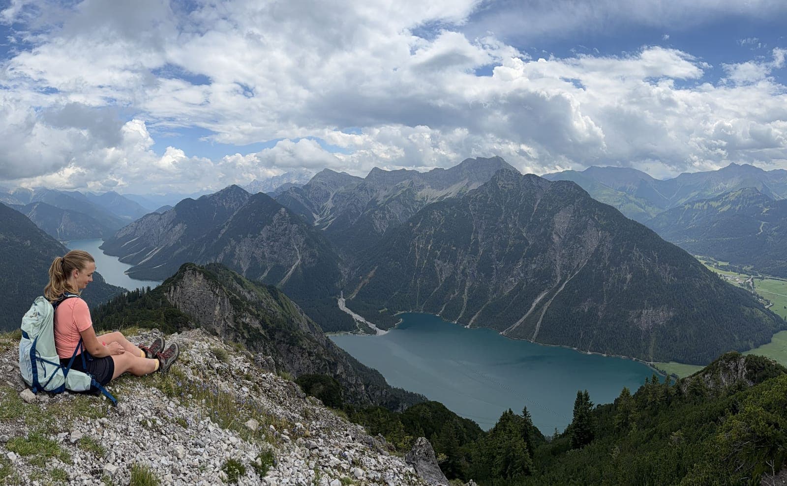 Anja sitzt auf einem Grat über einem Bergsee in den Alpen